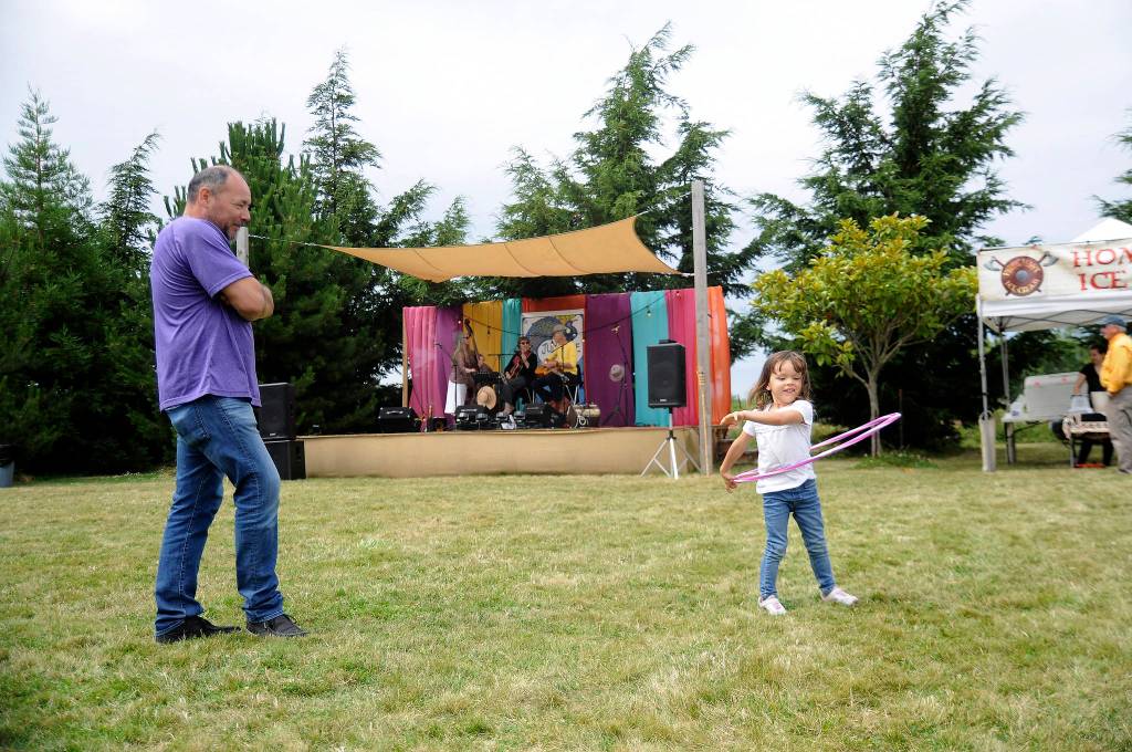 As Joe Ramirez looks on, Taylrin Ramirez, 4, works on her hula hoop skills as Stringology provides the musical backdrop at Jardin du Soleil Lavender on July 21. Sequim Gazette photo by Michael Dashiell