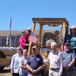 Sequim Museum & Arts Board of Trustees from bottom left, Nancy Goldstien, Bev Majors, Bob Stipe, Bob Clark and Bud Knapp; top left, Judy Reandeau Stipe, Greg Fisher, Hazel Ault (inside cab) and Trish Bekkevar stand where John Dickinson, owner of We Dig It Excavation, is preparing the ground for construction of Sequim Museum & Arts&rsquo; new exhibit building on North Sequim Avenue. Sequim Gazette photo by Erin Hawkins