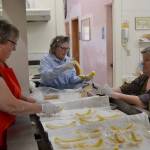 Sequim Prairie Grange members, from left, Philomena Lund, Joan Ritchie and Kim Moulson prepare banana splits for visitors at the Aug. 13 ice cream social in the Sequim Prairie Grange. The tradition has gone each summer as a fundraiser for local charities for 15-plus years. Sequim Gazette photo by Matthew Nash