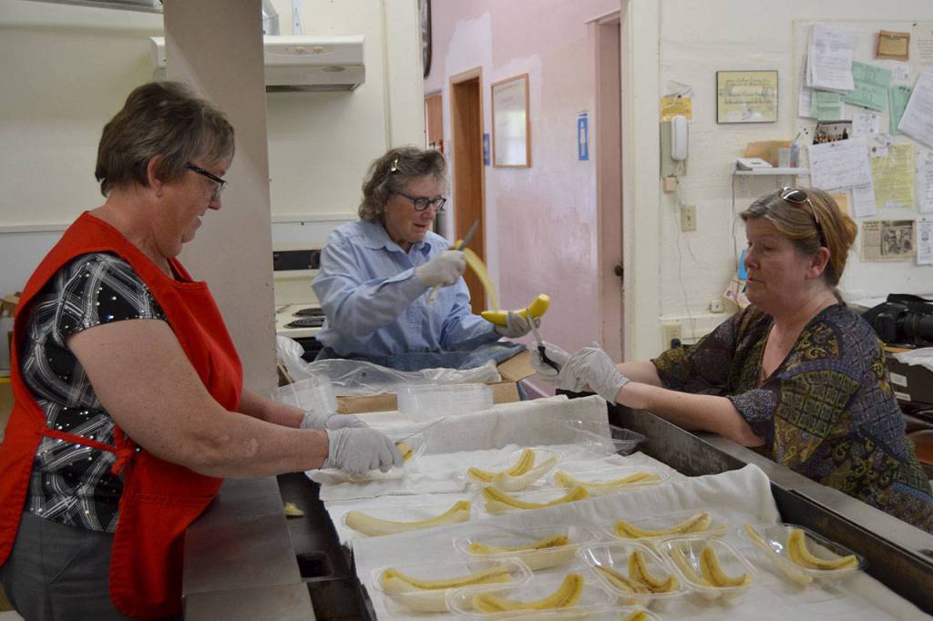 Sequim Prairie Grange members, from left, Philomena Lund, Joan Ritchie and Kim Moulson prepare banana splits for visitors at the Aug. 13 ice cream social in the Sequim Prairie Grange. The tradition has gone each summer as a fundraiser for local charities for 15-plus years. Sequim Gazette photo by Matthew Nash