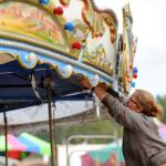 Amber Guy with Rainier Amusement of Portland, Ore., helps set up the merry-go-round at the Clallam County Fair on Aug. 14.