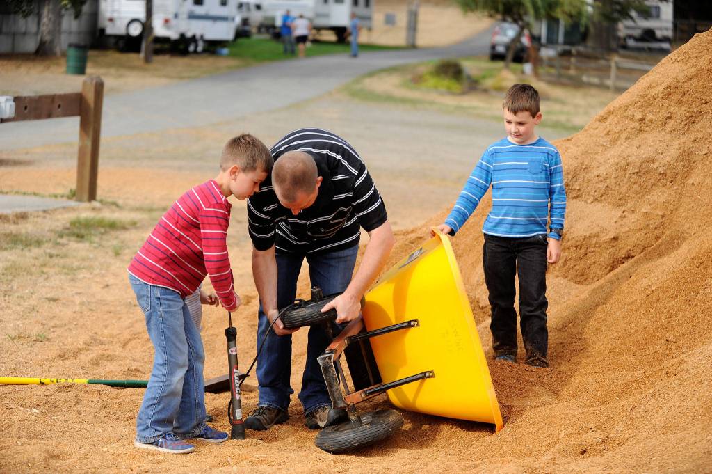 Jeff Bender with help from his sons Daniel, 9, left, and Grant, 8, right, try to fix a flat tire on a wheelbarrow outside the swine barn at the Clallam County Fair. Daniel belongs to Pure Country 4-H and will show pigs, rabbits and goats throughout the fair Aug. 17-20. Sequim Gazette photos by Matthew Nash