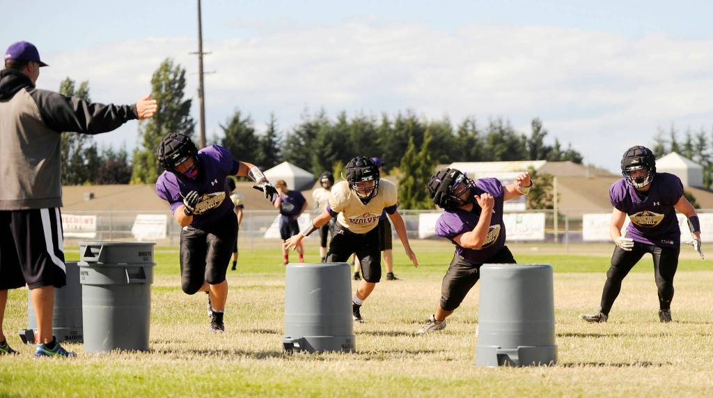Sequim coach Erik WIker (far left) leads a linebacker drill at a Sequim preseason practice last week. Sequim Gazette photos by Michael Dashiell