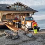Crews from Nickel Bros. help unload a 1916 Sears kit house off a barge onto Cline Spit on Oct. 9. Jim and Diane Luoma bought the house and moved it from Shelton. Photos by Bob Lampert