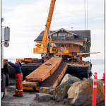 Crews from Nickel Bro. carefully unload Jim and Diane Luomas&rsquo; craftsman home off a barge onto Cline Spit. Photo by Bob Lampert