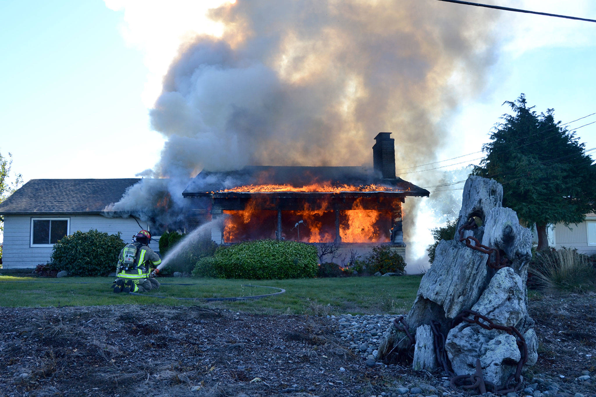 Firefighters with Clallam County Fire District 3 hose down the front of a home at 20 Thornton Drive on Oct. 27. Sequim Gazette photo by Matthew Nash