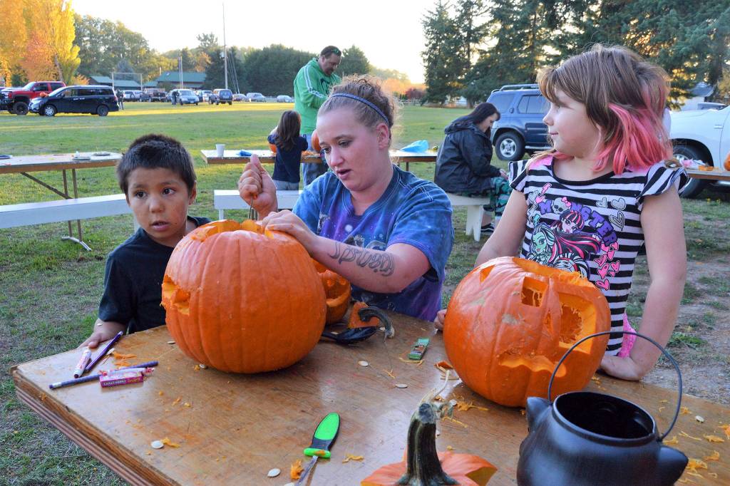 Lizziey Lowery carves a pumpkins with Damoni Gonzales, 5, and Ava Lowery, 6, at the Sequim Prairie Grange&rsquo;s Pumpkin Party. Sunny Farms donates the pumpkins each year, organizers said.