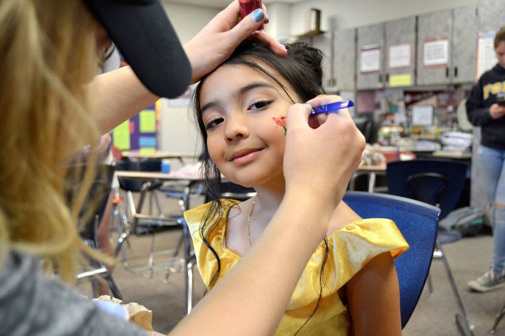 Sequim High Schooler Abby Norman paints a rose on 5-year-old Ariyana Lopez&rsquo;s face at Haunted Hallways on Oct. 28. Ariyana and her sister Leyla, 1 ½, both dressed as Belle from &ldquo;Beauty and the Beast.&rdquo;