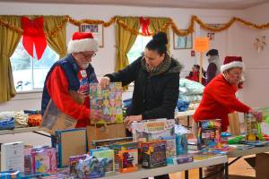 Volunteers Joel Ogden and Anne Notman with Sequim Community Aid help Sheena Touchard look for toys at last years Toys for Sequim Kids. Organizers said 400 children in Sequim received items from the event in 2016. This year, the event is set for Dec. 13, at the Sequim Prairie Grange. Sequim Gazette photo by Matthew