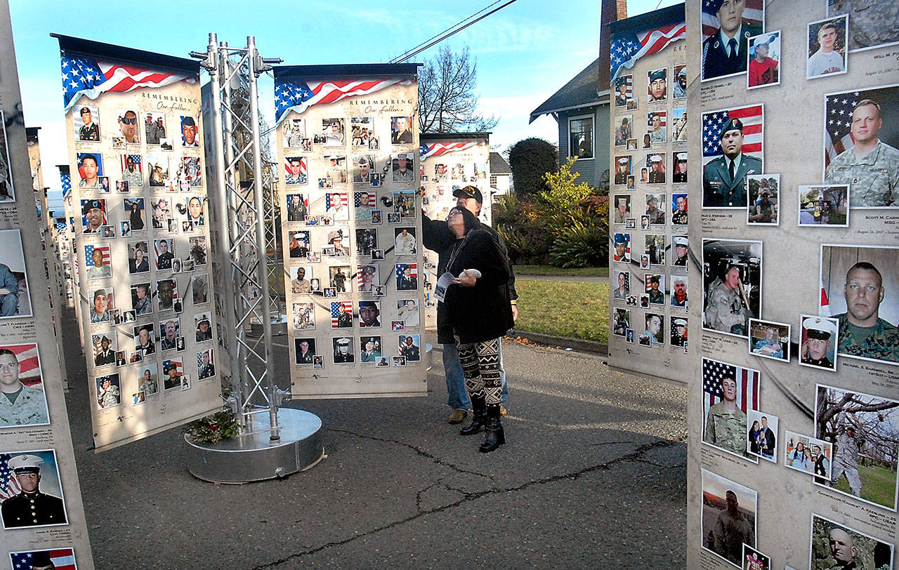 Jeff and Kathy Thayer of Port Angeles look through the photos of military personnel killed since Sept. 11, 2001 at the Remembering Our Fallen  traveling memorial in Port Angeles. Photo by Keith Thorpe/Peninsula Daily News