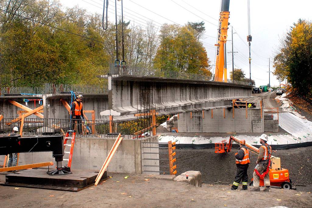A crew from Ness Cranes of Seattle hosts the last of four 148-foot reinforced concrete beams into place in early November for what will become the new Old Olympic Highway bridge spanning McDonald Creek west of Sequim. The new bridge replaces a narrower 1957-vintage span that was considered too narrow and inadequate for modern traffic. Photo by Keith Thorpe/Olympic Peninsula News Group
