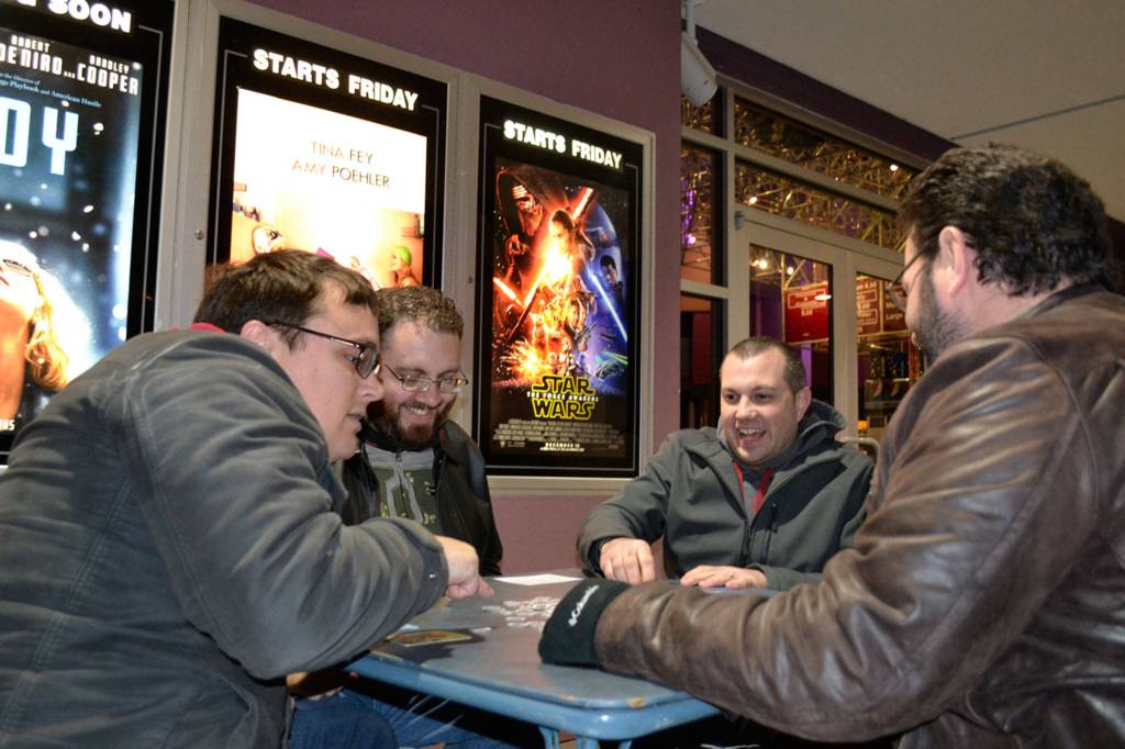 Friends, from left, Jesse Reynolds, Ryan French, Mike French and Ken Smith with Benjamin Komar (not pictured) play card games waiting for the 3-D showing of Star Wars Episode VII: The Force Awakens on opening night, Thursday, Dec. 17, 2015. Some of the sounds from the original films come from animals formerly living in Sequim. Sequim Gazette photo by Matthew Nash