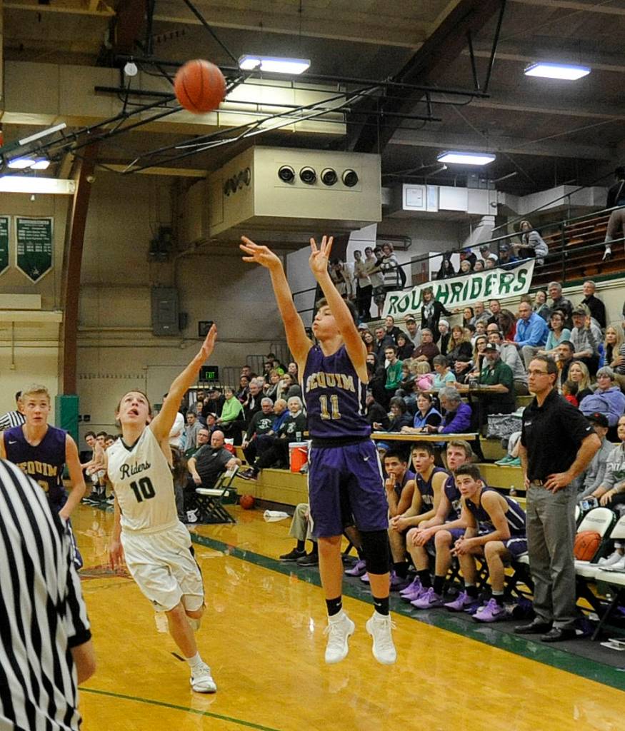 Sequim reserve guard Michael Young connects on a 3-pointer as Sequim coach Greg Glasser and fellow Wolves look on. Port Angeles Gary Johnson III (10) defends the play. Sequim Gazette photo by Michael Dashiell