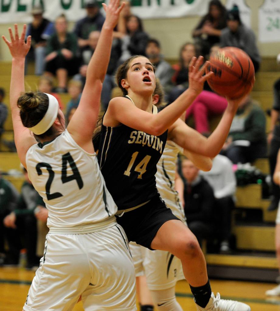 Sequims Hope Glasser, right, drives past Port Angeles defender Aeverie Politika for a basket in Sequims 44-17 loss to the host Roughriders on Dec. 13. Sequim Gazette photo by Michael Dashiell