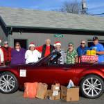Olympic Peninsula Chapter of Club Miata Northwest members gather with Stephen Rosales, board president of the Sequim Food Bank, around Vicki Burr-Chellins 2008 Miata MX5 for a donation on Dec. 14 of $350 and several boxes of food. Sequim Gazette photo by Matthew Nash