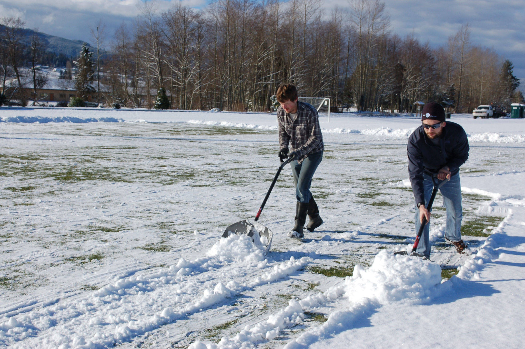 Employee of Meyer Electric, Taylor McCormack, left, and Meyer Electric owner and president of Storm King Soccer Club Kyle Kautzman, shovel snow on Feb. 22 at the Albert Haller Playfields at Carrie Blake Park so the Storm King Soccer Clubs Boys U10 team can practice for their game on Feb. 24. Sequim Gazette photo by Erin Hawkins