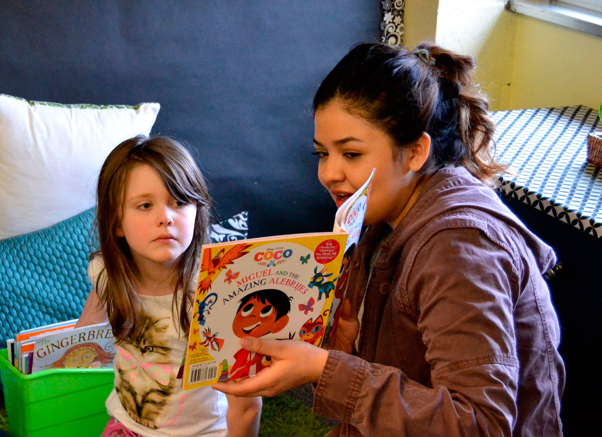 At left, Sequim High Schooler Stephanie Lemus reads to kindergartner Lyric Marsh in Stephanie Grotzke-Nashs class a story based on the movie Coco.