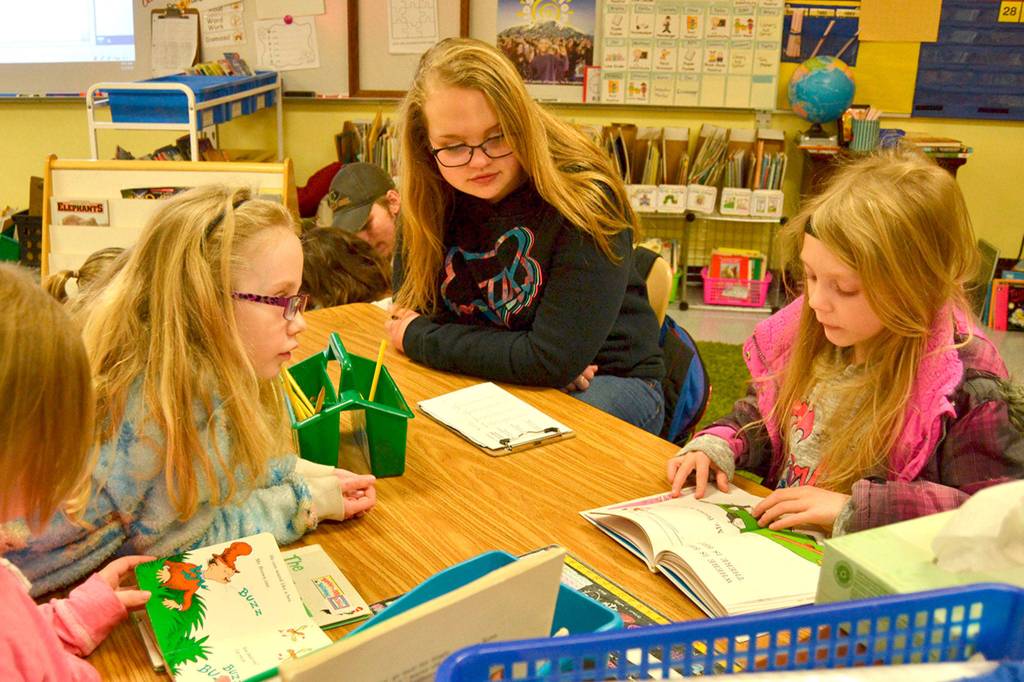 Sequim High Schooler Alyssa Rothganger, center, sits in on a classic Dr. Seuss tale in Bettina Hoesels first grade class at Helen Haller Elementary as Chloe Seymour reads and Trinity Devlin listens in. Sequim Gazette photos by Matthew Nash