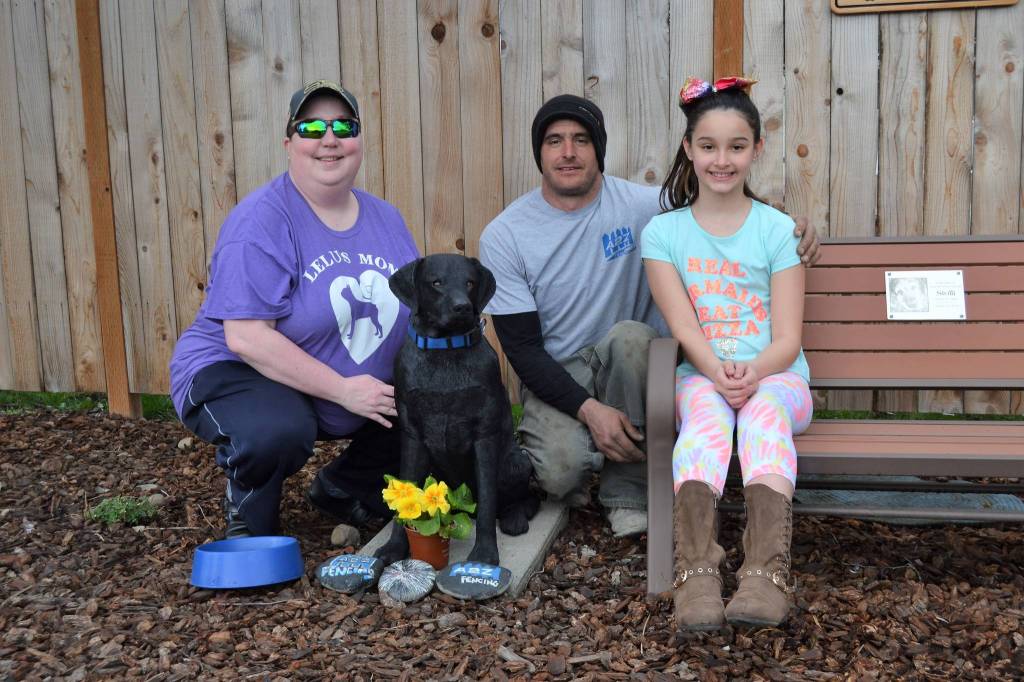 Jen Frame, co-moderator of the Sequim, WA Facebook community page, Kevin Cassidy and his daughter Alabama stand by the newest Stolli the dog statue in front of A2Z Fencing earlier this week. Cassidy recently installed the statue after community members raised funds to bring in a new statue after it was broken and stolen. Stolli was the Cassidys family dog who was popular among locals. Sequim Gazette photo by Matthew Nash