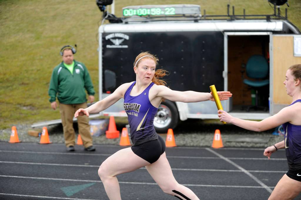 Sequims Kiara Pierson takes a handoff from teammate Mary McAleer as the Wolves race to first place in the 4x200 relay at the March 29 Flying A Retro meet in Port Angeles. Sequim clocked in at 1:57.44. Sequim Gazette photo by Michael Dashiell