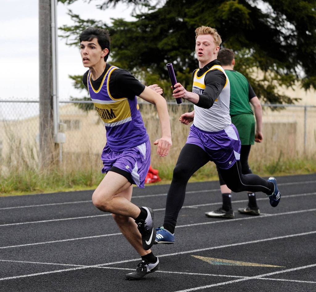 Darren Salazar, left, snags the baton from teammate Logan Laxson in the 4x100 relay at last weeks track and field meet in Port Angeles. With teammates Silas Isenberger and Alec Shingleton, the team raced to first place in 45.97 seconds. Sequim Gazette photo by Michael Dashiell