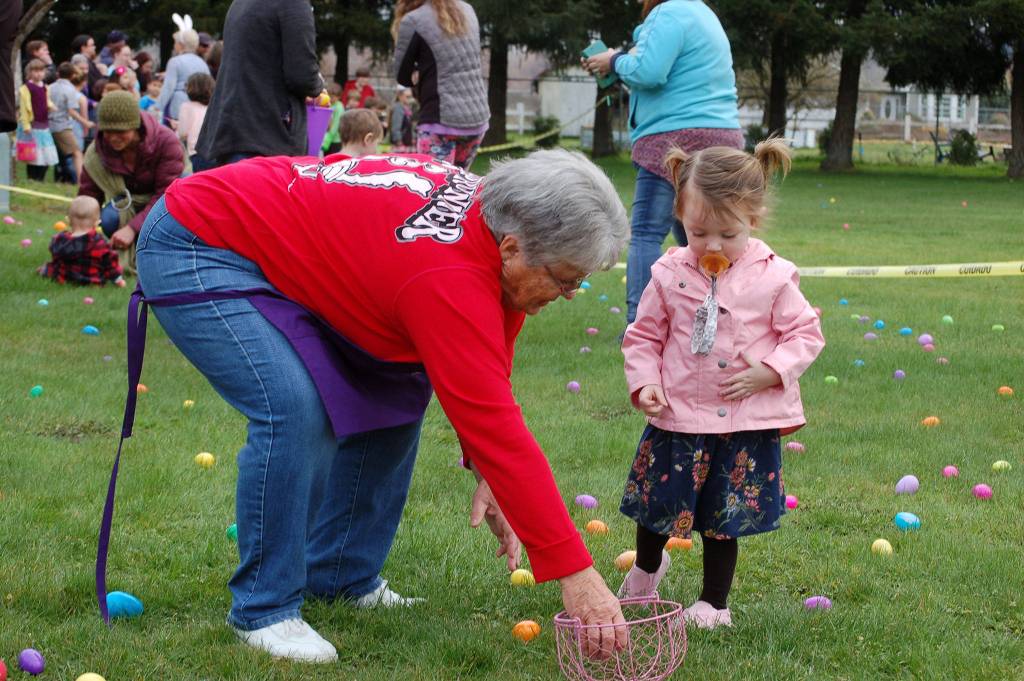 Elks Lodge member Sharon Blanken, left, helps Aria Cummings, 2, put eggs in her basket at the Elks Lodge Easter egg hunt on March 31. Sequim Gazette photo by Erin Hawkins