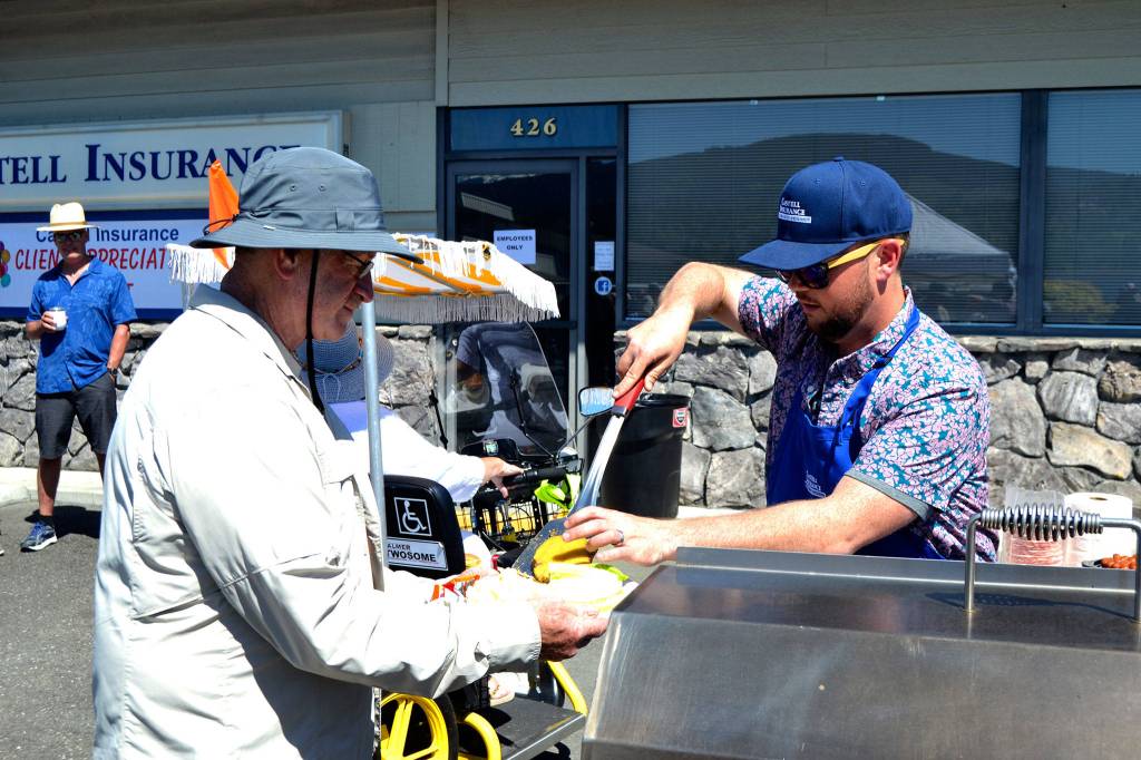 James Castell serves up a hamburger to Dan Knutson of Sequim before the Grand Parade at Castell Insurances Client Appreciation Barbecue prior to the Grand Parade. Sequim Gazette photo by Matthew Nash