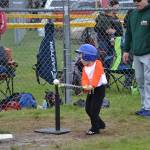 Reed Nash takes a swing as T-ball coach John Coon looks on during a game earlier this season. For many players, it was their first experience on a team sport. Sequim Gazette photo by Matthew Nash