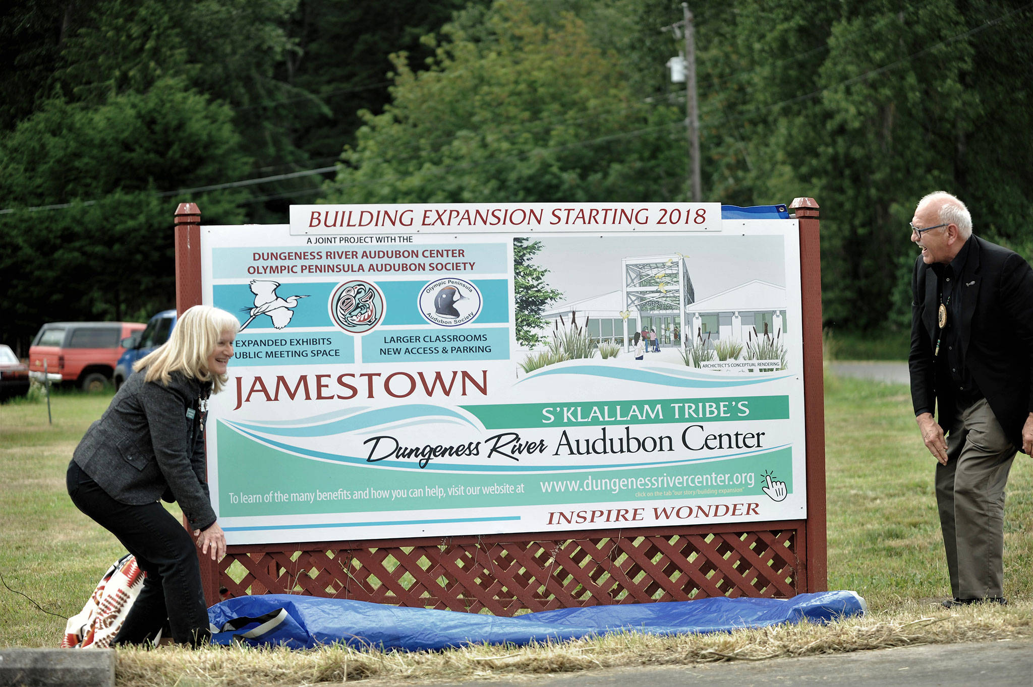 Annette Hanson, capital campaign committee chair for the expansion of the Dungeness River Audubon Center, and Ron Allen, tribal chairman for the Jamestown SKlallam Tribe, reveal a new sign on June 22 at the entrance to the Railroad Bridge Park announcing the campaign to build a new parking lot and expand the center. Sequim Gazette photo by Matthew Nash