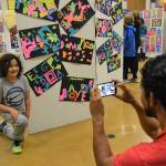 Erik Cisneros snaps pictures of his son Edgar Cisneros, 8, at the Helen Haller Elementary Art Show that included works he followed the style of artists like Henri Matisse. Edgar took art classes after school from Kaylee Kinsey and Renee Mullikin.
