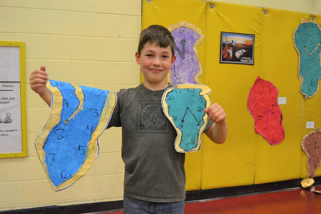 Noah Andrzejeski, 9, from Rachel Odens third grade art class stands with his pieces following the style of Salvador Dali. Noah said he likes the colors and how the clocks melt and droop.