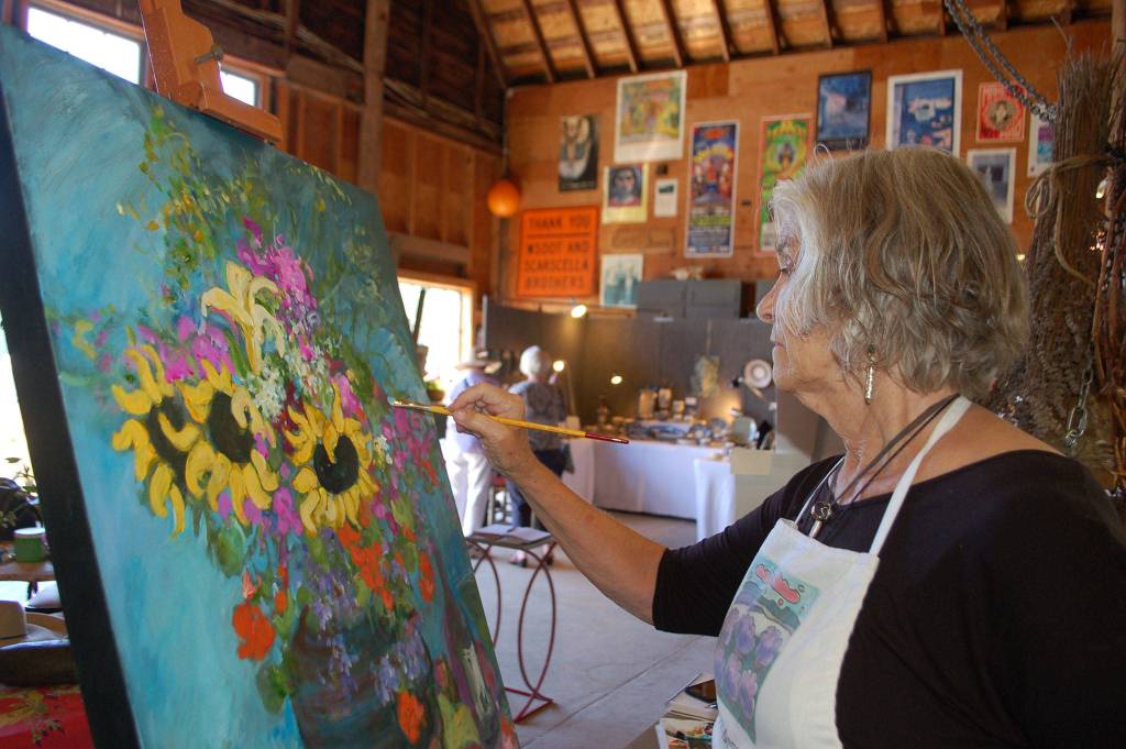 Art Jam artist and demonstrator Lynne Armstrong works on an acrylic painting in the barn at Rock Hollow Farm during Sequim Lavender Weekend.