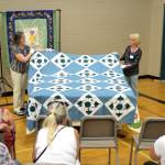 Barbara McArthur, left, and Nancy Davison of the Sunbonnet Sue Quilt Club turn a quilt made by Laura Hutzlers at-the-time 97-year-old grandmother. The quilt was one of many quilts displayed during the clubs annual show July 20-22. Sequim Gazette photo by Matthew Nash