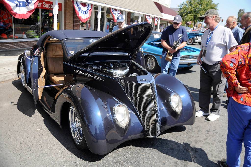 Attendees at the Sequim Prairie Nights car show last year look at Steve Pillows 1937 Ford coupe that took Peoples Choice. This years show features more than a dozen trophies. Sequim Gazette file photo by Michael Dashiell