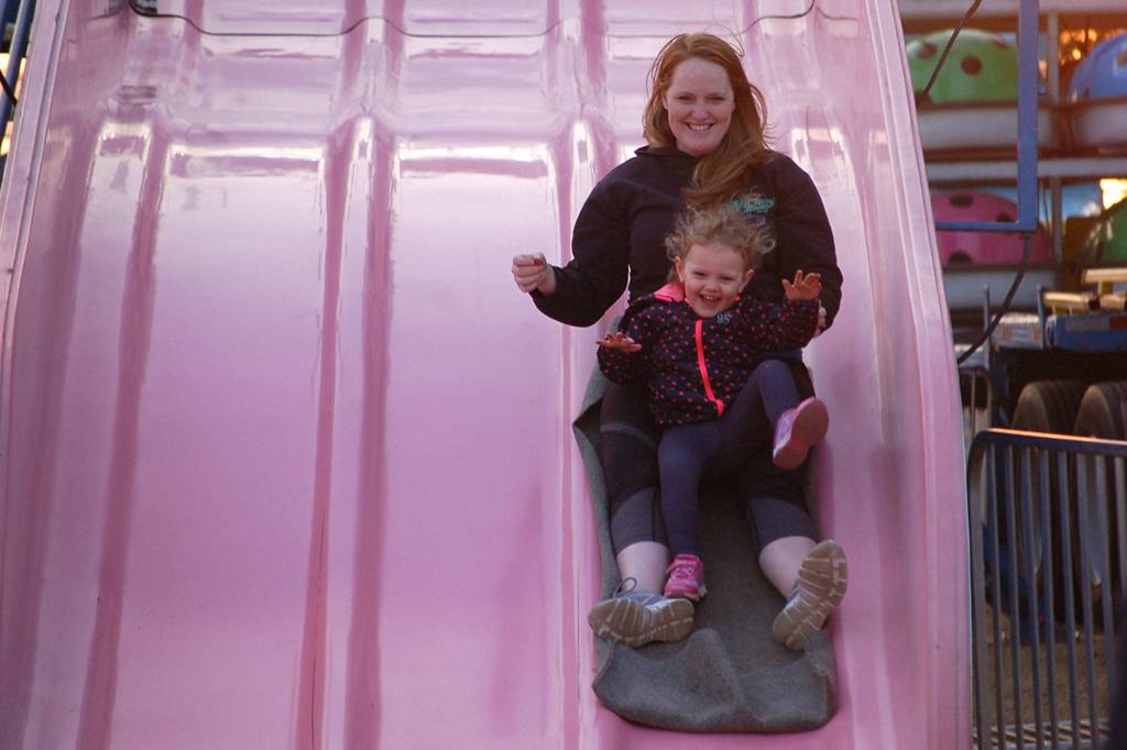 Michele Billings of Port Angeles and her daughter Isabella, 2, ride together down the giant slide at the Clallam County Fair on Aug. 17.