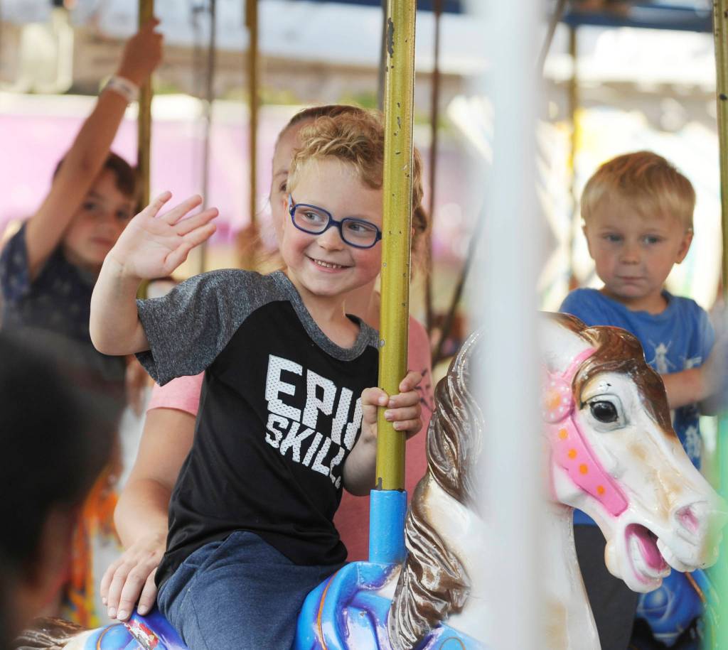 Port Angeles youngsters Carson Tillia, 4, and brother Evan, 3, take a ride on the carousel with mom Danielle at the Clallam County Fair carnival on Aug. 18.