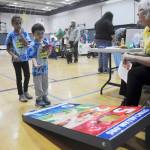 Charlie Petersen, 5, and Chelsea, 8, learn a bit about healthy living while playing a beanbag toss game at the Olympic Peninsula Healthy Community Coalition booth at Saturdays Back to School Fair, with help from volunteer Patty Shoop (right). Sequim Gazette photo by Michael Dashiell
