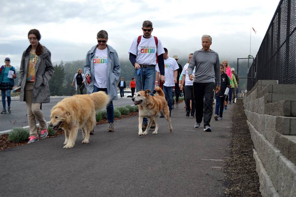 Lisa Boulware and Mark Ozias walk with their dogs while talking with Eric Lewis, chief executive officer for Olympic Medical Center on Saturday, Sept. 8 during the Sequim Free Clinics Fun Walk. Sequim Gazette photo by Matthew Nash