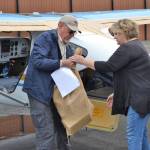 Ray Ballantyne, a volunteer with Disaster Aircraft Response Team hands a bag of food to Andra Smith, Sequim Food Bank executive director, on Sept. 15, at the Sequim Valley Airport.   Sequim Gazette photo by Matthew Nash
