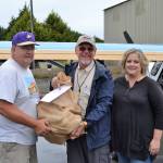 For the first of three trips, Ray Ballantyne, a volunteer with Disaster Aircraft Response Team (DART), in middle, hands a bag of food to Stephen Rosales, Sequim Food Bank board president, and Andra Smith, Sequim Food Bank executive director, on Sept. 15, at the Sequim Valley Airport. The event was a coordinated through DART to test a response plan following a catastrophic event and merged into a food drive, as well. Sequim Gazette photo by Matthew Nash