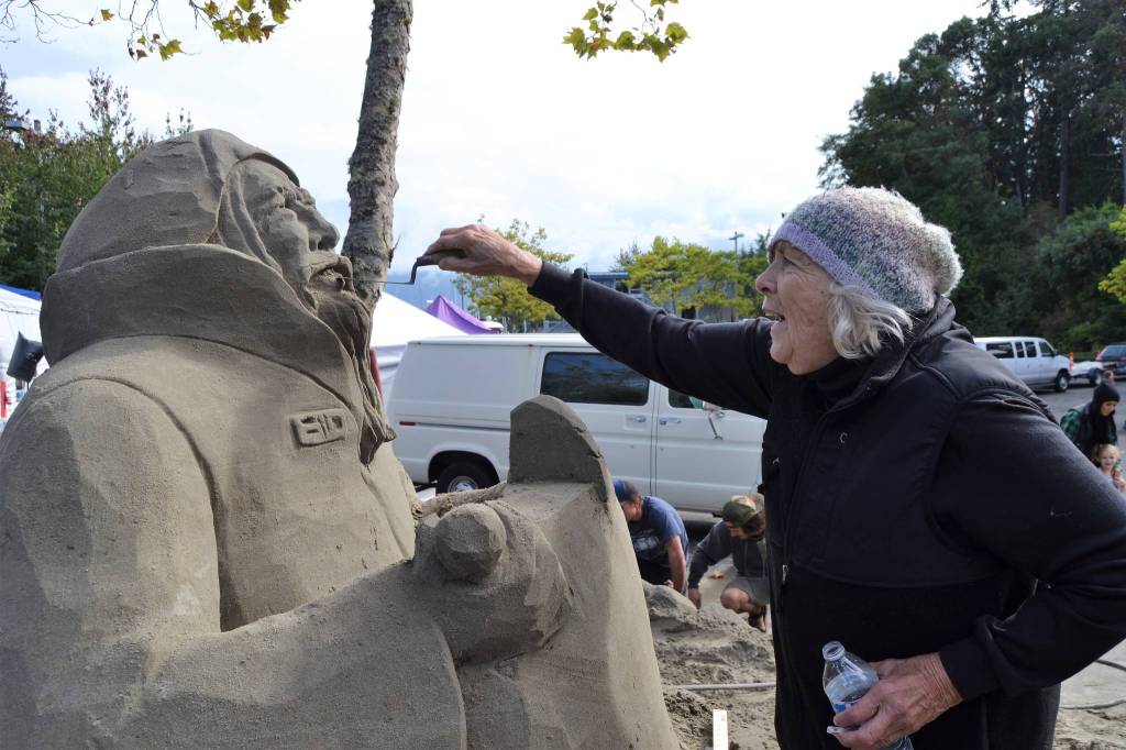 Kali Bradford looks to finish the face of her Artful Sailor sand sculpture on Sept. 15 at the John Wayne Marina for Waterfront Day with help from her grandsons Jeremiah and Alexander Schroeder. Hes a sailor fighting a storm obviously on his way home, she said. Sequim Gazette photo by Matthew Nash