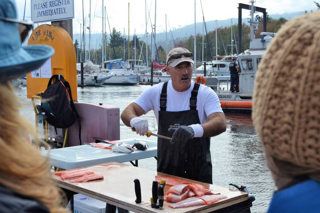 Chris Jafay of Dun Rite fish filleting shows a small crowd his work on the docks at the John Wayne Marina during Waterfront Day on Sept. 15. Sequim Gazette photo by Matthew Nash