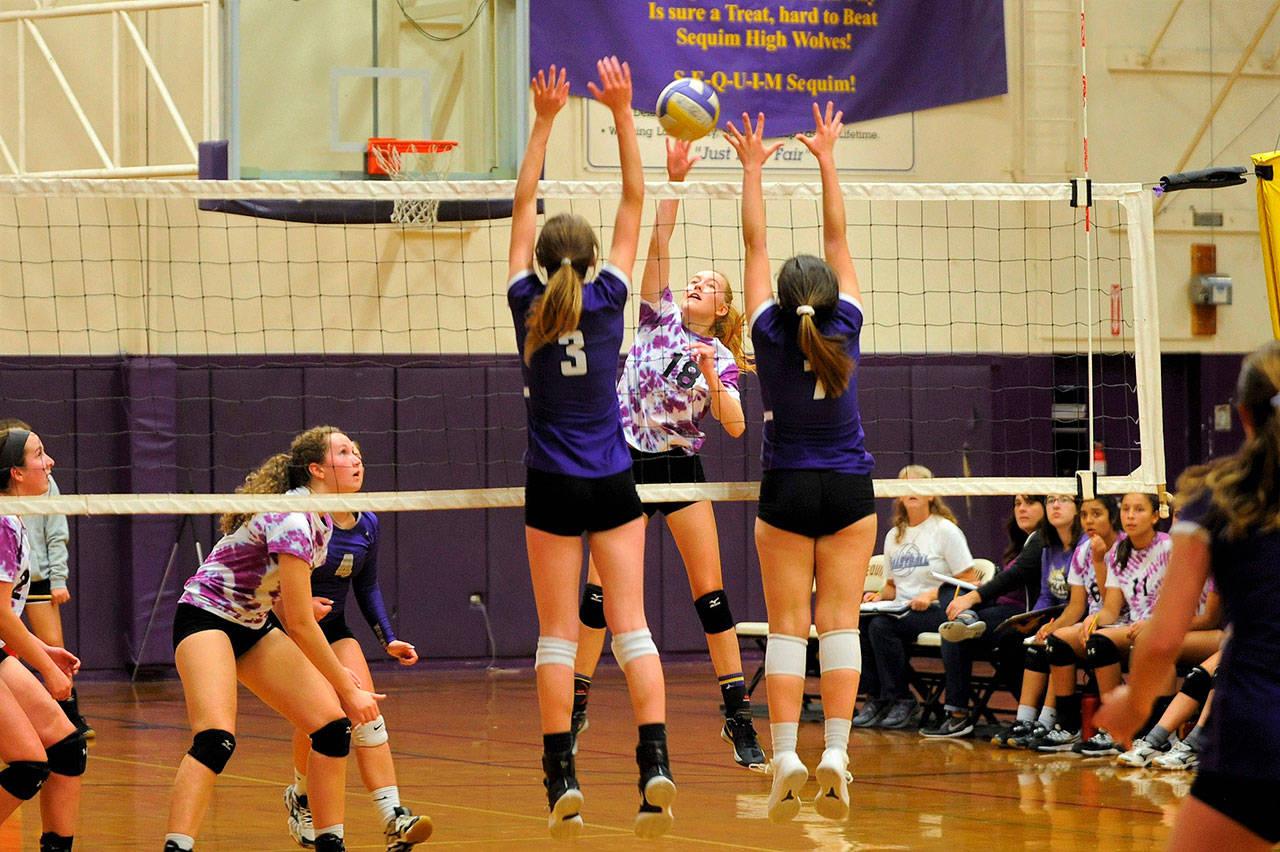 Sequims Annika Christiansen (18) looks to hit between the blocks of North Kitsap defenders Taylyn Boop (3) and Autumn Carver (7) in the Wolves five-game loss to the No. 1-ranked Vikings on Oct. 11. Sequim Gazette photo by Matthew Nash