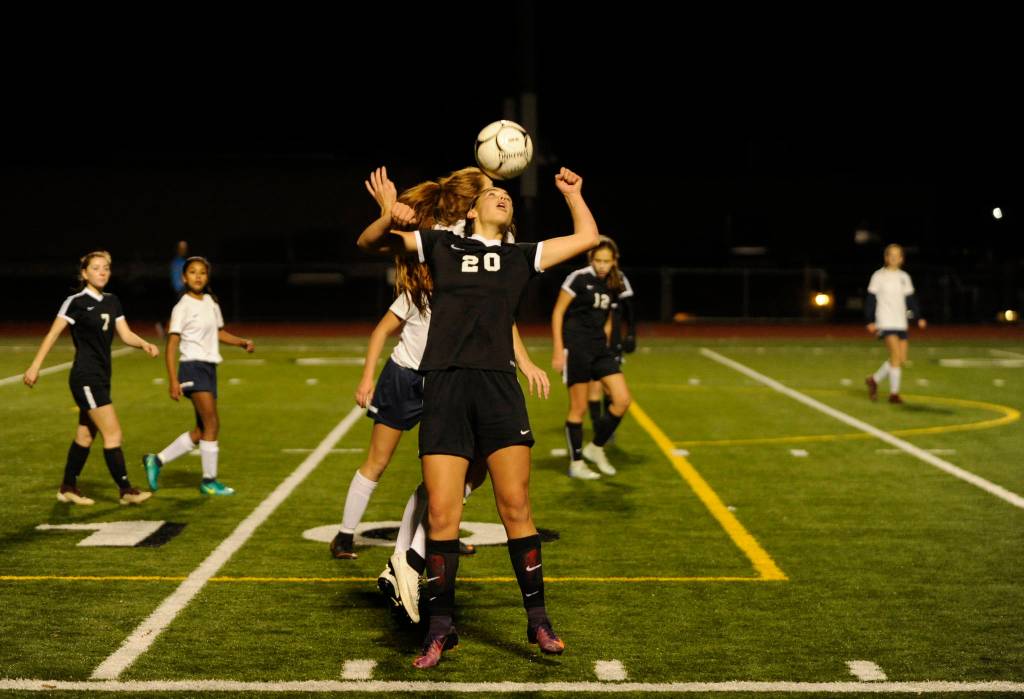 Sequims Hope Glasser (20) heads the ball over an Ellensburg defender in the first half. Sequim Gazette photo by Michael Dashiell