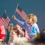 Charlotte Johnson of Sequim, 4, waves an American flag during the Veterans Day ceremony at U.S. Coast Guard Air Station/Sector Field Office Port Angeles on Sunday. (Jesse Major/Peninsula Daily News)
