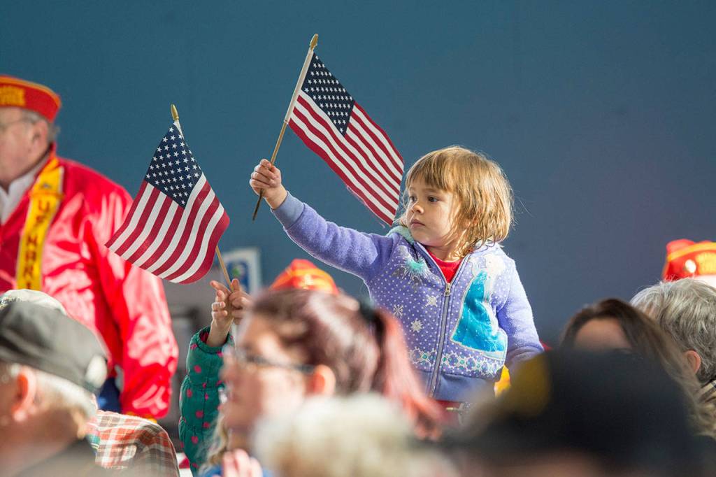 Charlotte Johnson of Sequim, 4, waves an American flag during the Veterans Day ceremony at U.S. Coast Guard Air Station/Sector Field Office Port Angeles on Sunday. (Jesse Major/Peninsula Daily News)
