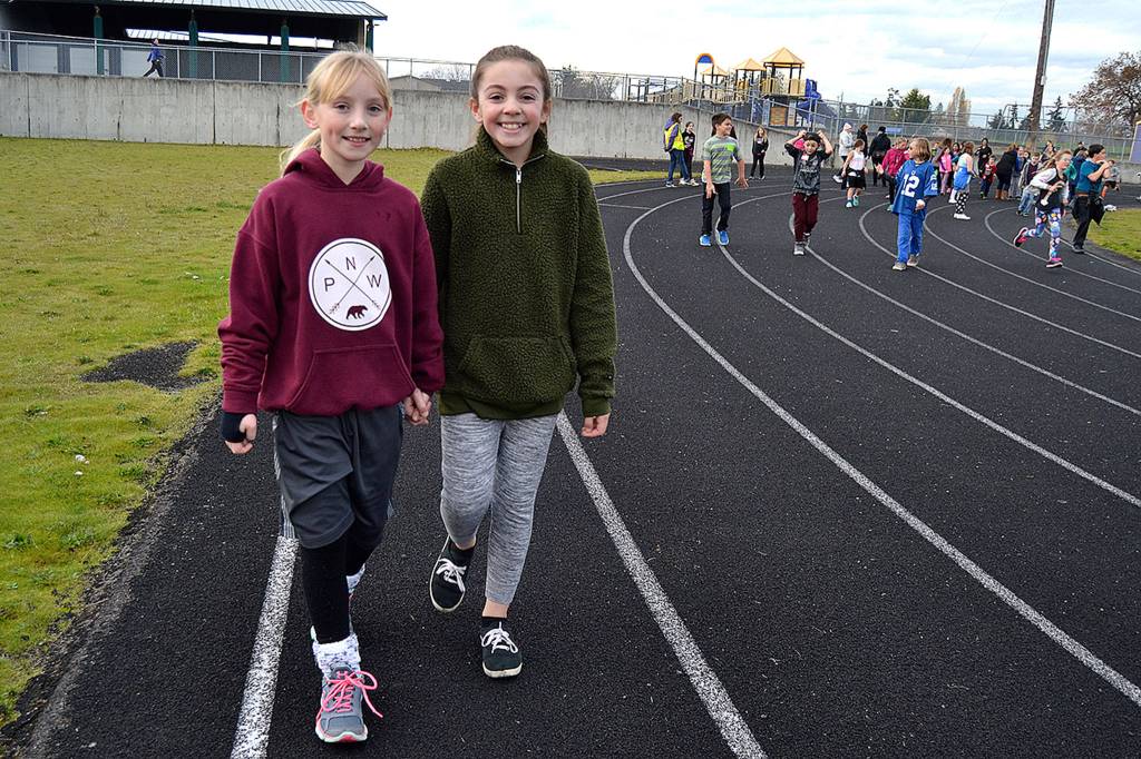 Friends Grace Minty and Mady Salazar walk hand-and-hand around the track during Helen Haller Elementarys Turkey Trot. Sequim Gazette photo by Matthew Nash