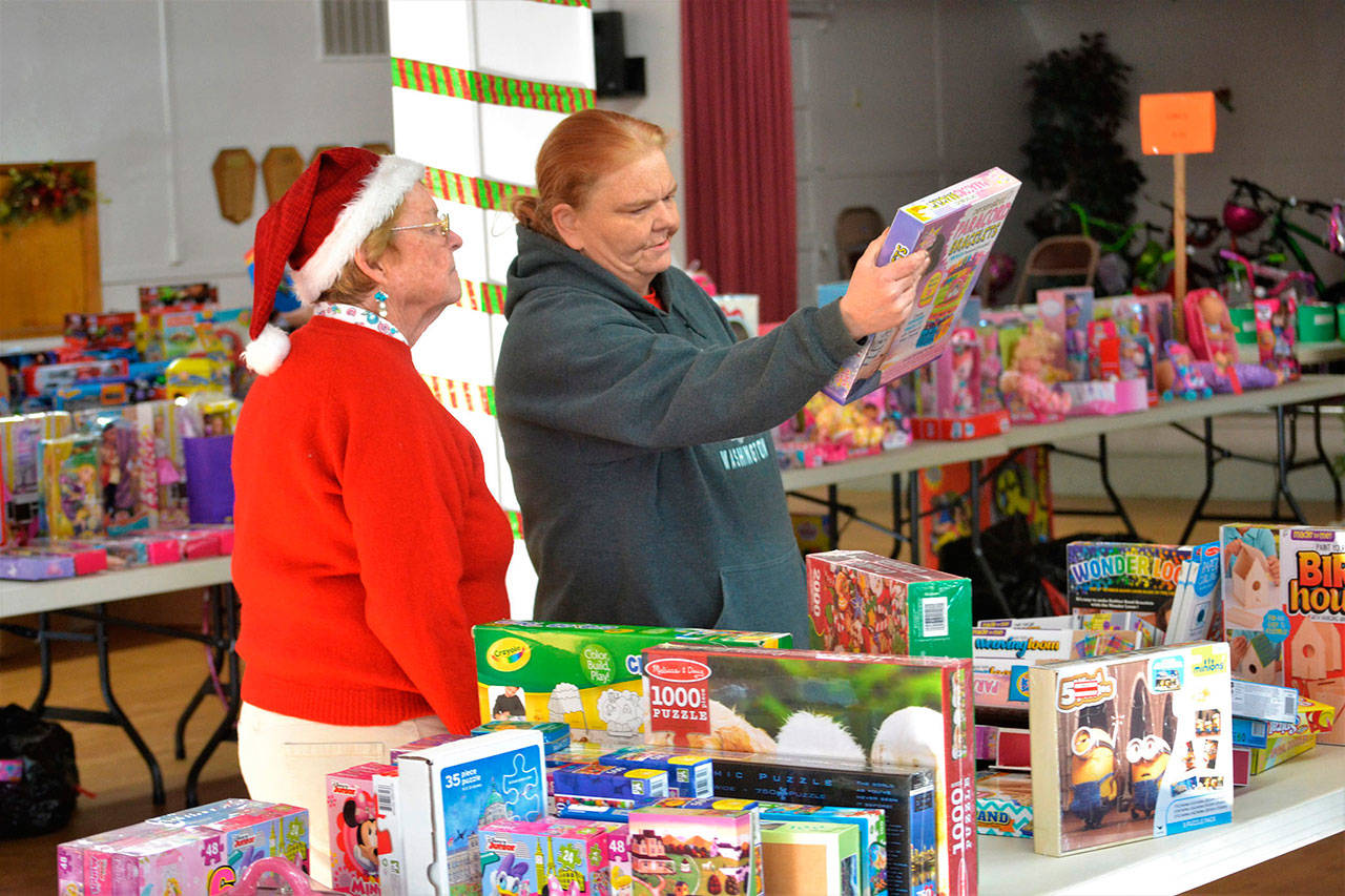 Last year, Toys for Sequim Kids helped bring toys to nearly 400 Sequim children, including Lori Seimers children. Here she looks for toys with Anne Notman, a volunteer with Sequim Community Aid in 2017. Donations continue through Dec. 10 around the community. Sequim Gazette photo by Matthew Nash