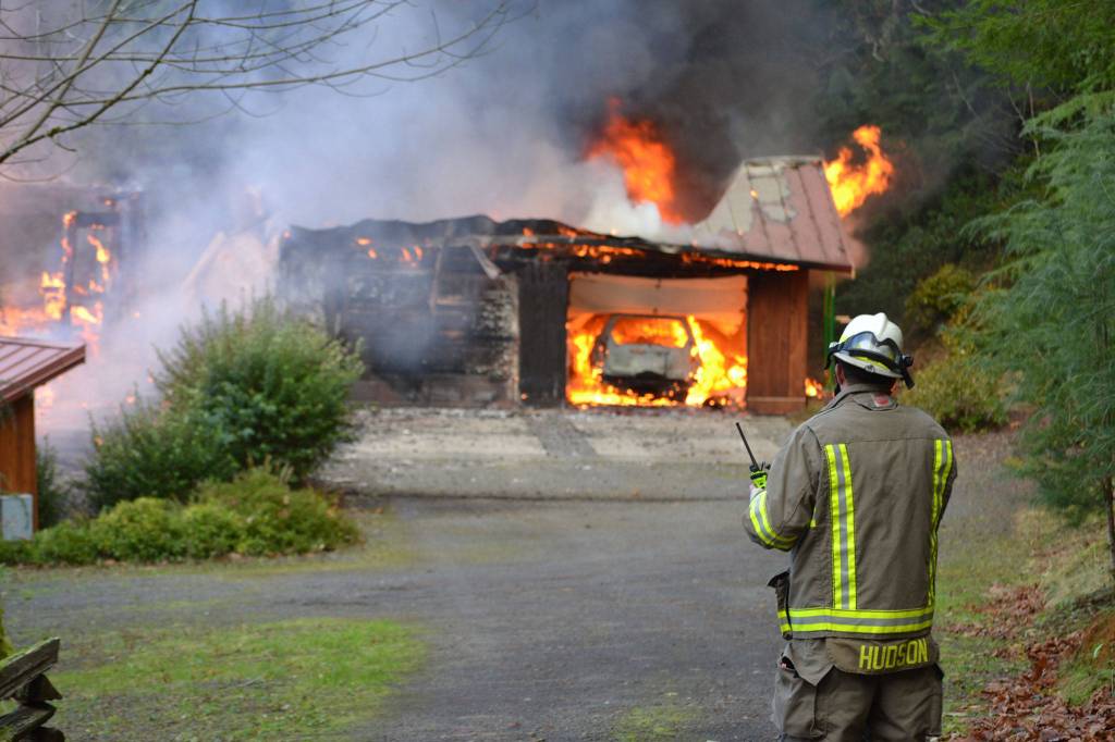 Assistant Fire Chief Tony Hudson reports in about the fire as he awaits a water tender to arrive to fight the Blyn fire from atop a steep hill. Sequim Gazette photo by Matthew Nash
