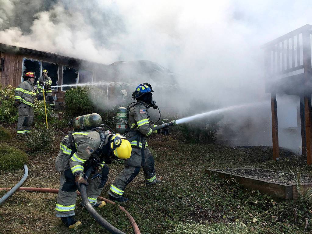 Clallam County firefighters attempt to combat flames on a Blyn house fire on Dec. 3. Sequim Gazette photo by Matthew Nash